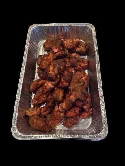 A foil tray of grilled meat ready to serve, at Coyoteville in Alice, Texas