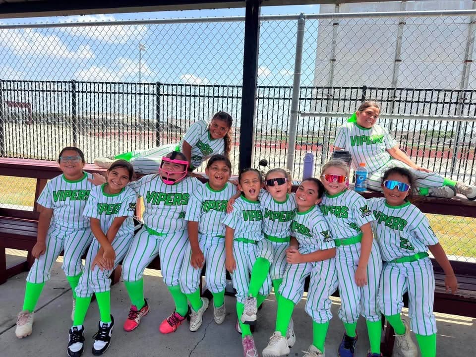 A youth softball team in green and white Vipers uniforms together in the dugout, an Alice organization that sets up at Coyoteville in Alice, Texas