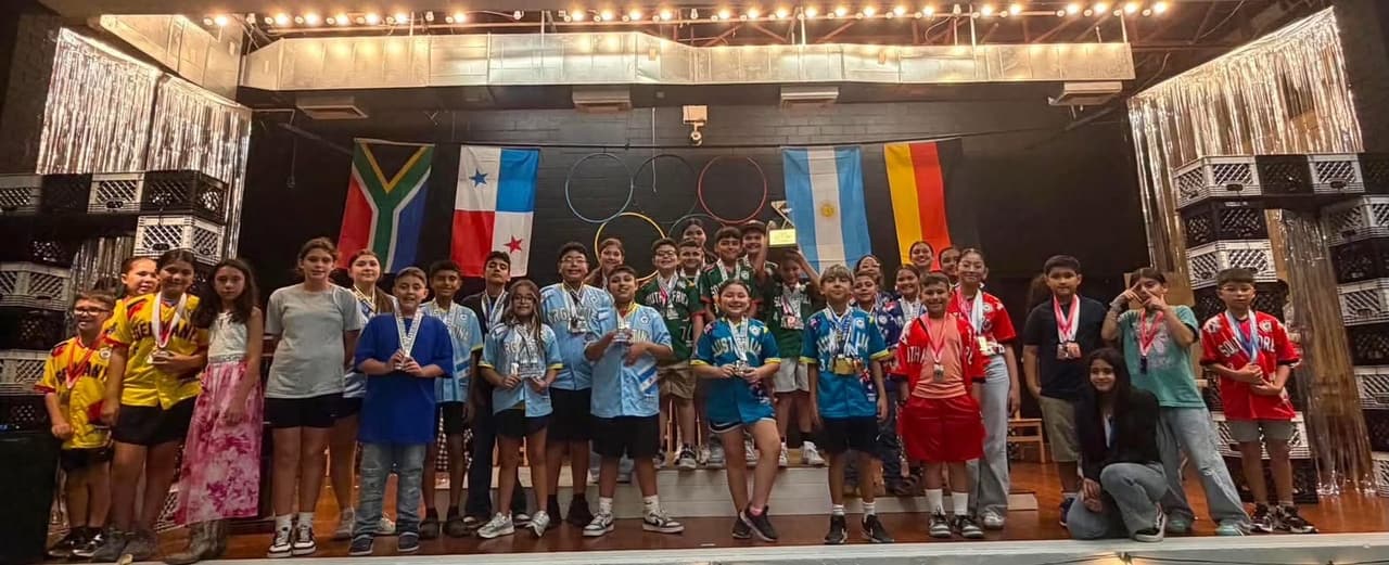 A youth group on stage with flags behind them, an Alice organization that sets up at Coyoteville in Alice, Texas